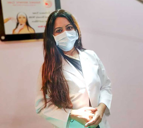 Dr. Poonam Arya standing in her clinic, wearing white coat and operating equipment
