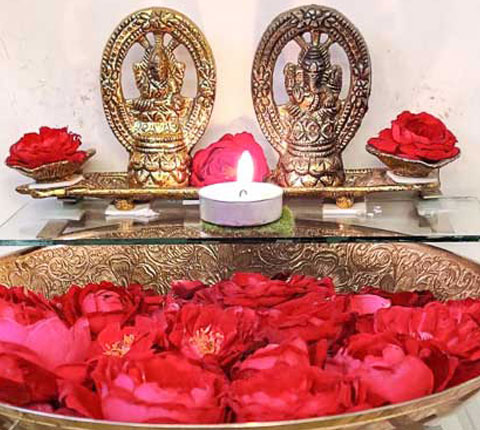 Golden colored idols of Indian deity Ganesh and Laxmi and placed in front of them a diya and flowers